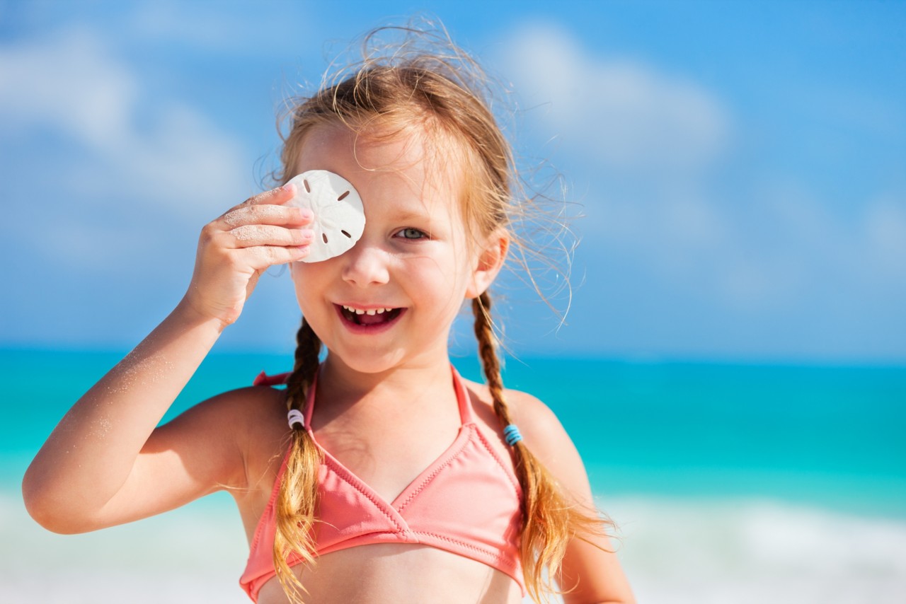 Adorable little girl at beach holding sand dollar