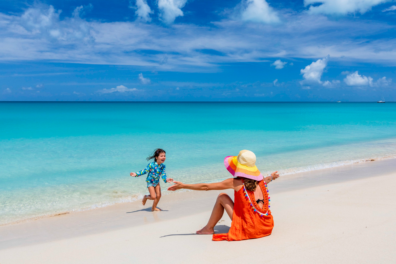 Young mother playing with her little daughter on a white sand beach, Barbuda, Antigua & Barbuda, Caribbean, West Indies