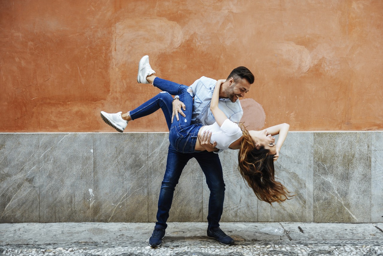 Spain, Andalusia, Granada. Young couple in love having fun in front of a wall outdoors. Lifestyle concepts