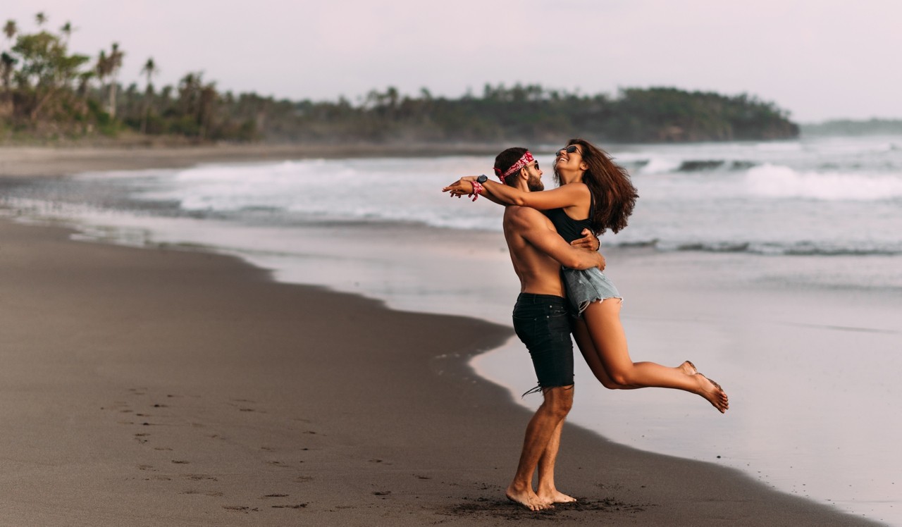 Couple on their honeymoon. Couple travels the world. Happy couple on vacation. Man and woman traveling to Bali. Holidays on beautiful Islands. Lovers meet the sunset on the sea. Happy couple at sunset