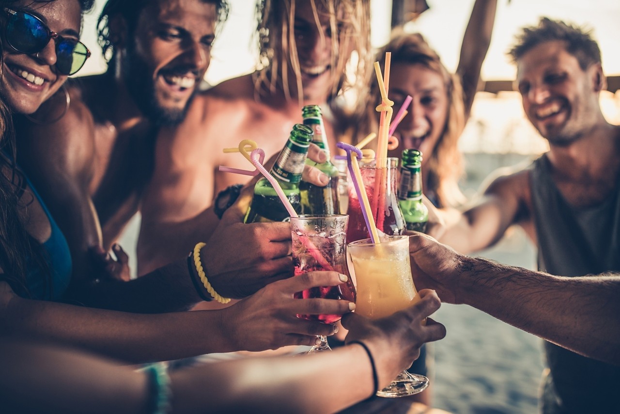 Close up of happy people having fun on a party while toasting with alcohol.