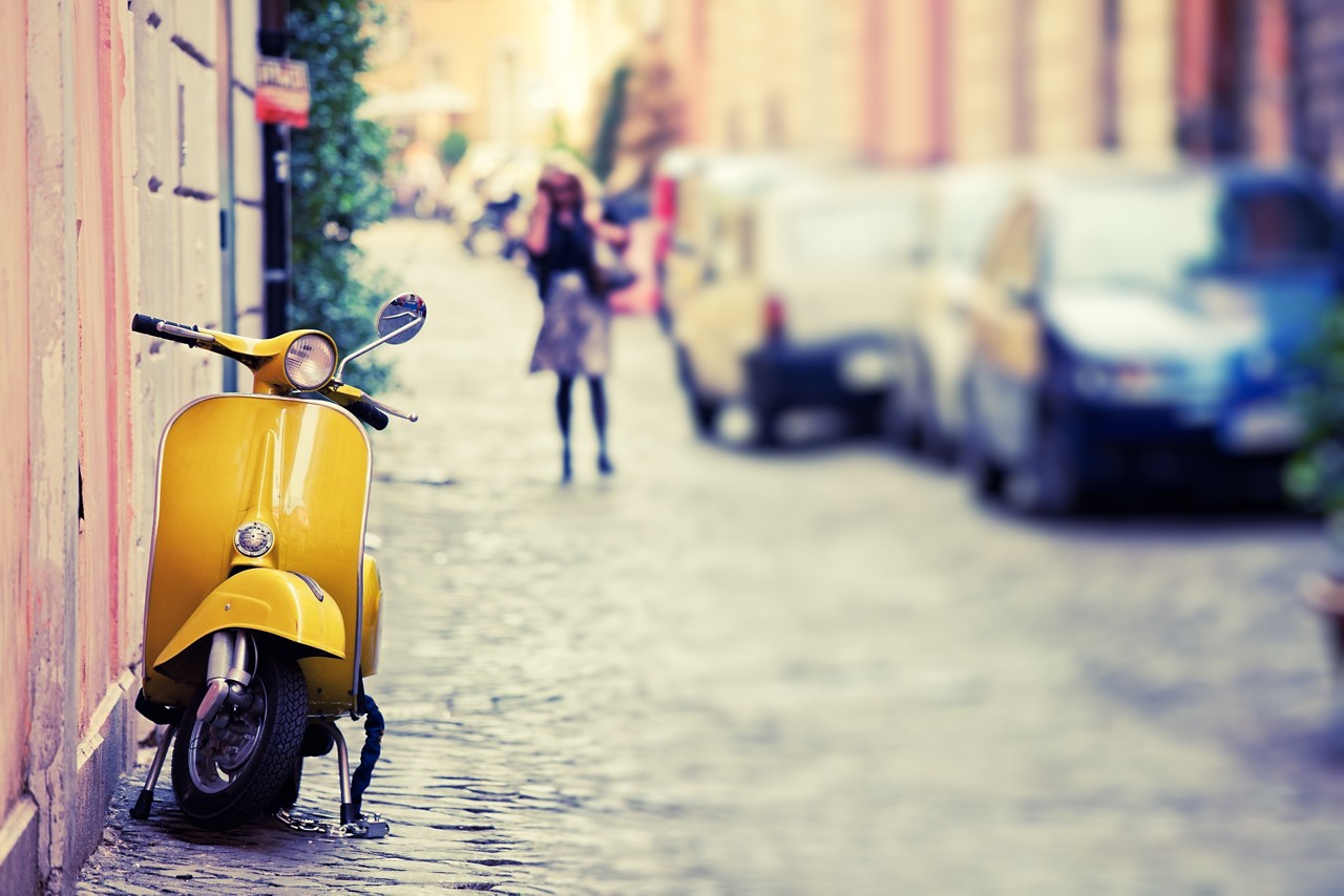 "Italian urban scene with a Vespa, a very typical italian motorcycle, tilt shift lens"
