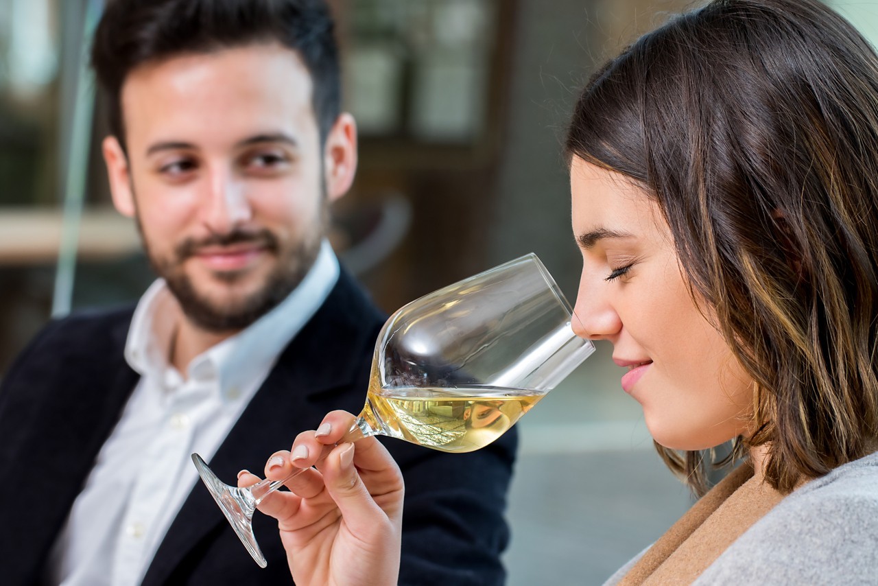 Close up portrait of young woman smelling white wine aroma at tasting.