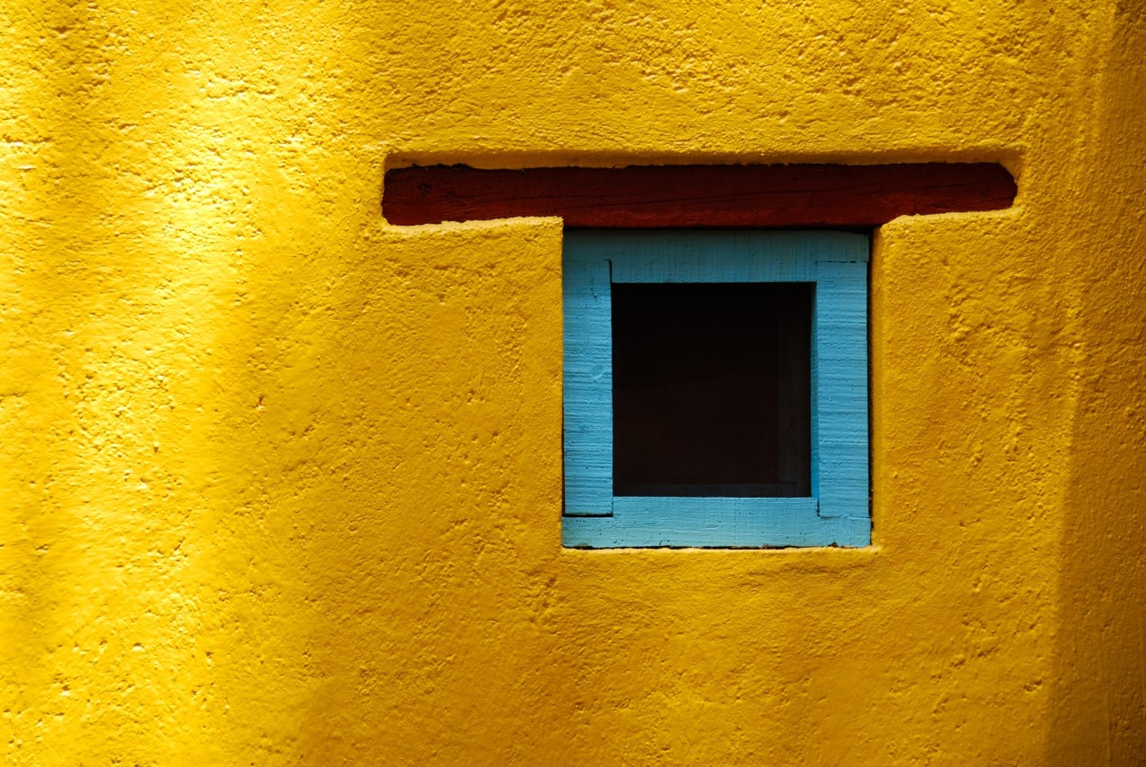 Rustic window in San Miguel de Allende, Spanish colonial town in Mexico. Blue turquoise window on a yellow wall.