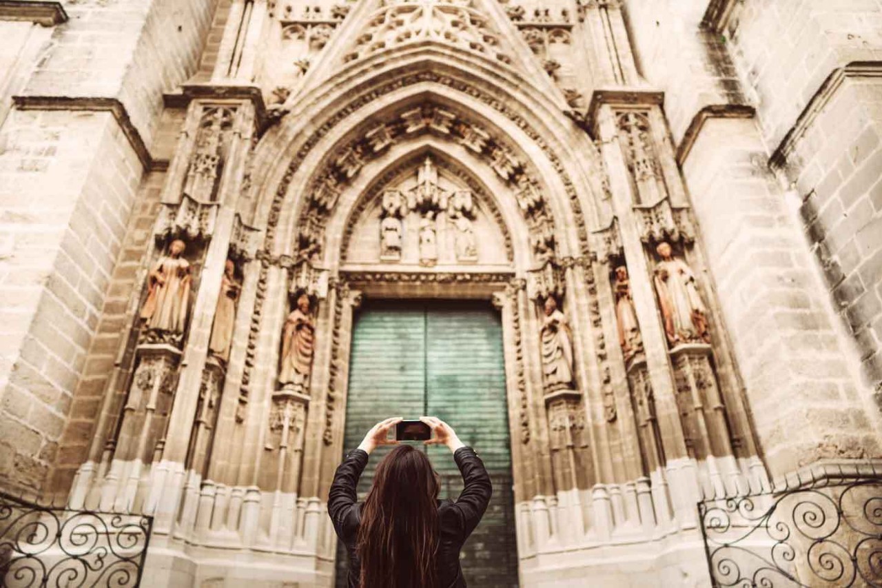 Sichere Reiseziele für alleinreisende Frauen: Städtetrip in Spanien, Frau fotografiert Kathedrale.
