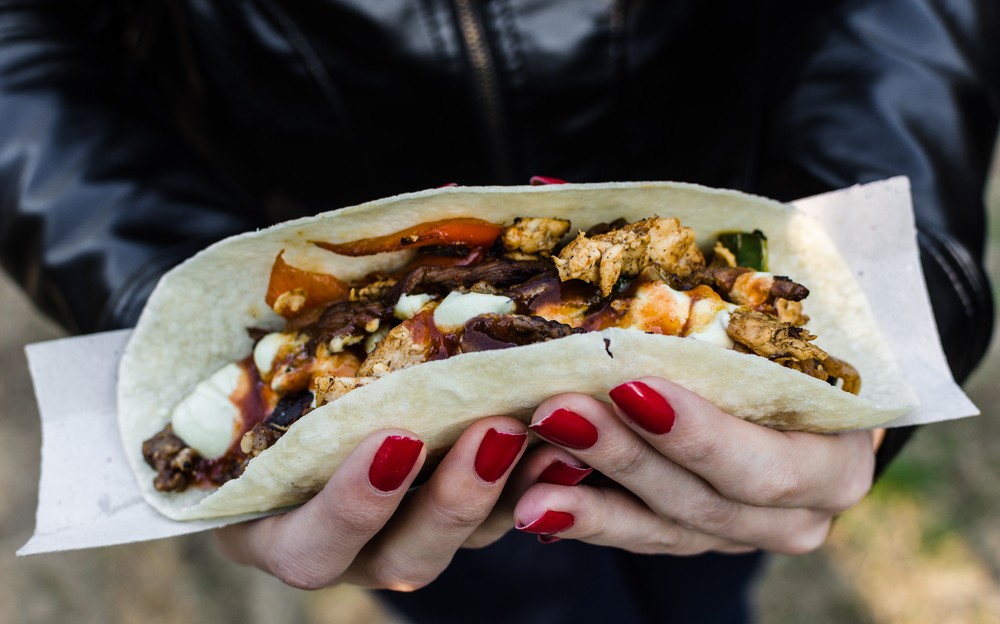 Close up photo of a traditional Mexican taco with beef filling at a street food market. Selective focus.
