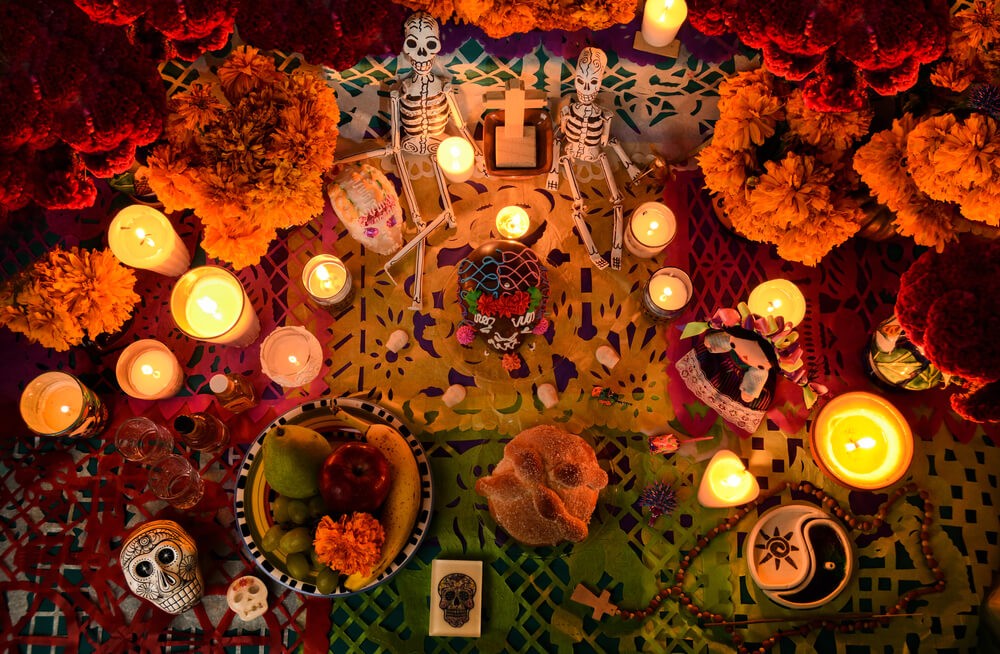Tag der Toten in Mexiko: Altar mit Blumen, Kerzen, Skeletten, Totenköpfen und Speisen.