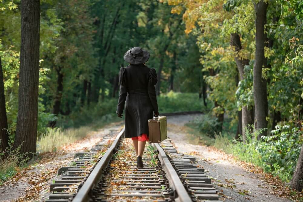 Berühmte Abenteurerinnen: Frau mit Koffer auf einem Bahngleis
