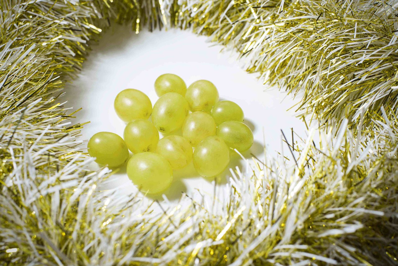 Latin American New Year’s traditions: A handful of grapes on a white table surrounded by tinsel