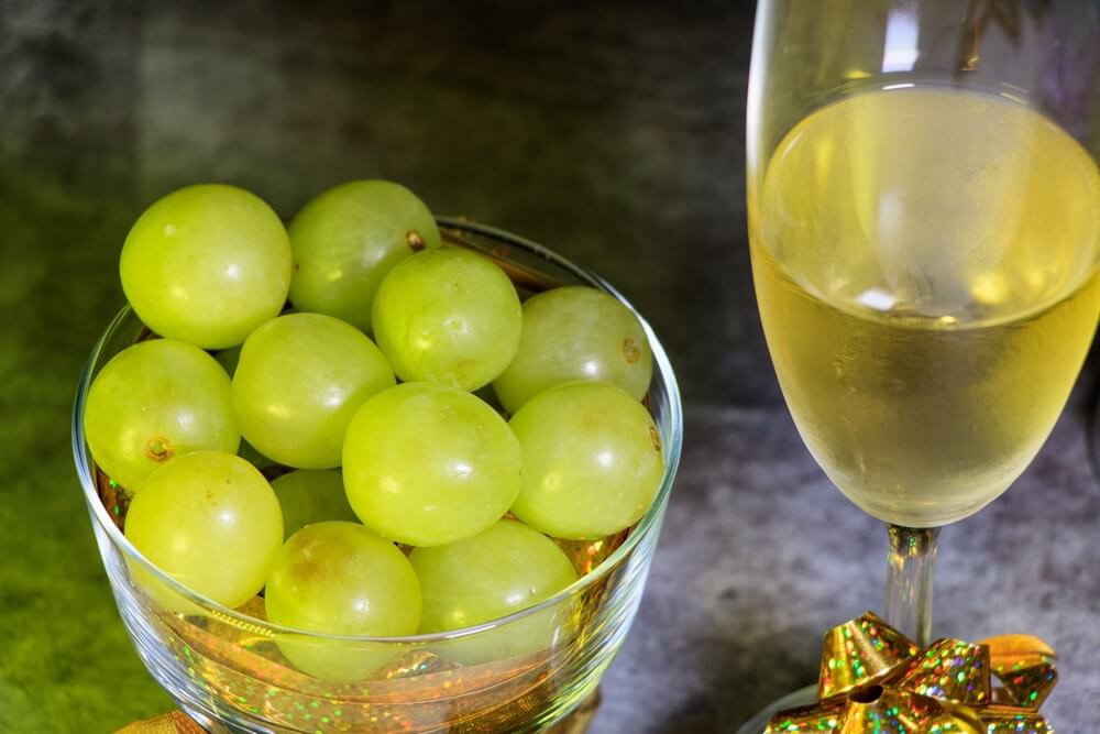 Latin American New Year’s traditions: A handful of grapes on a white table surrounded by tinsel